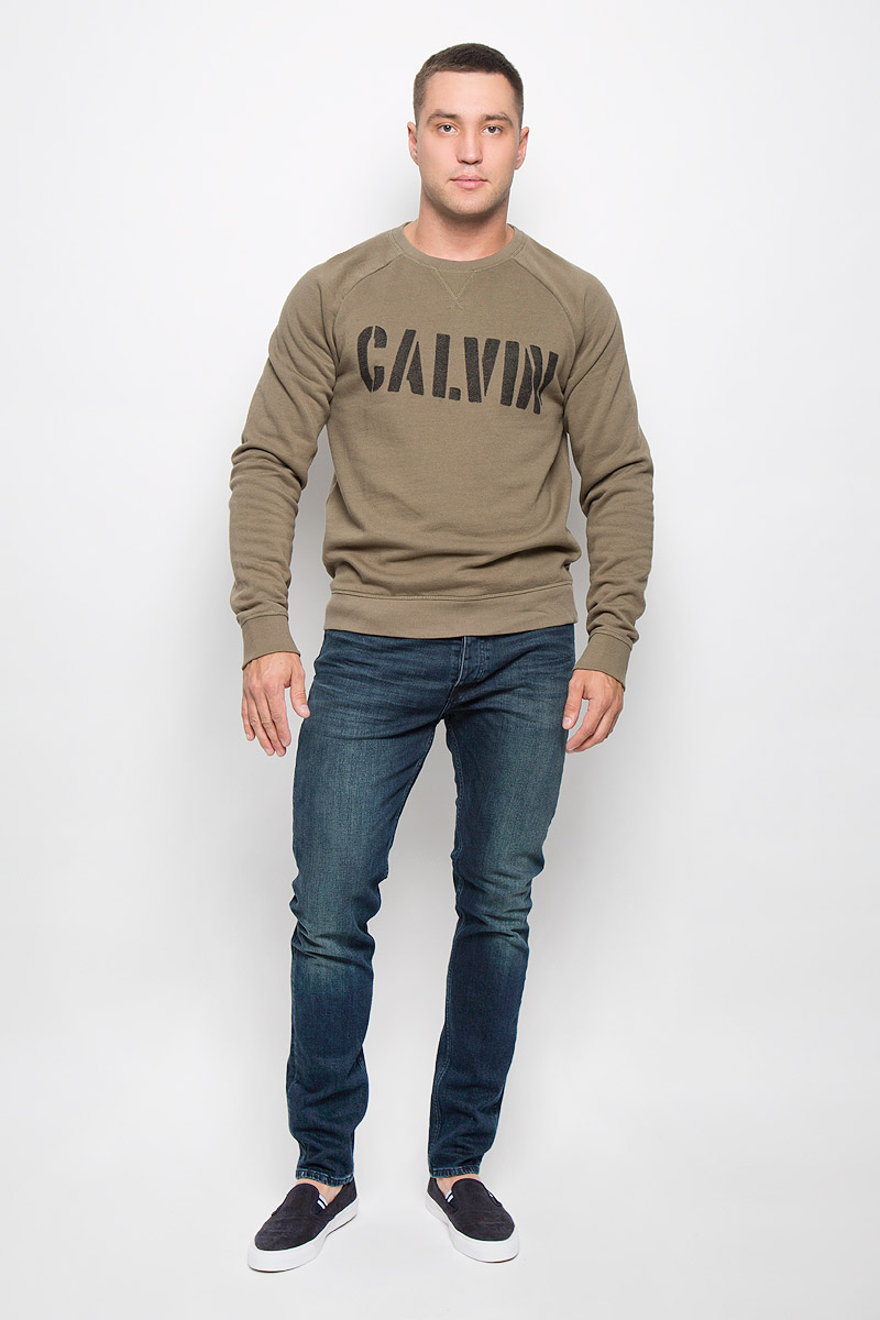 Cвитшот мужской Calvin Klein Jeans, цвет: хаки. J30J300142_3460. Размер XXL (52/54)SSP2261BE Cвитшот мужской Calvin Klein Jeans, цвет: хаки. J30J300142_3460. Размер XXL (52/54)SSP2261BEСтильный мужской свитшот Calvin Klein Jeans, изготовленный из высококачественного хлопка с добавлением полиэстера, мягкий и приятный на ощупь, не сковывает движений и обеспечивает наибольший комфорт. Такой свитшот великолепно пропускает воздух, позволяя коже дышать, и обладает высокой гигроскопичностью, а также превосходно отводит влагу от тела, оставляя кожу сухой после занятий спортом.Модель свободного кроя с круглым вырезом горловины и длинными рукавами-реглан оформлена крупным принтом с надписью Calvin. Манжеты рукавов, воротник и низ изделия дополнены трикотажными резинками. Этот свитшот - настоящее воплощение комфорта, он послужит отличным дополнением к вашему гардеробу. В нем вы будете чувствовать себя уютно в прохладное время года.