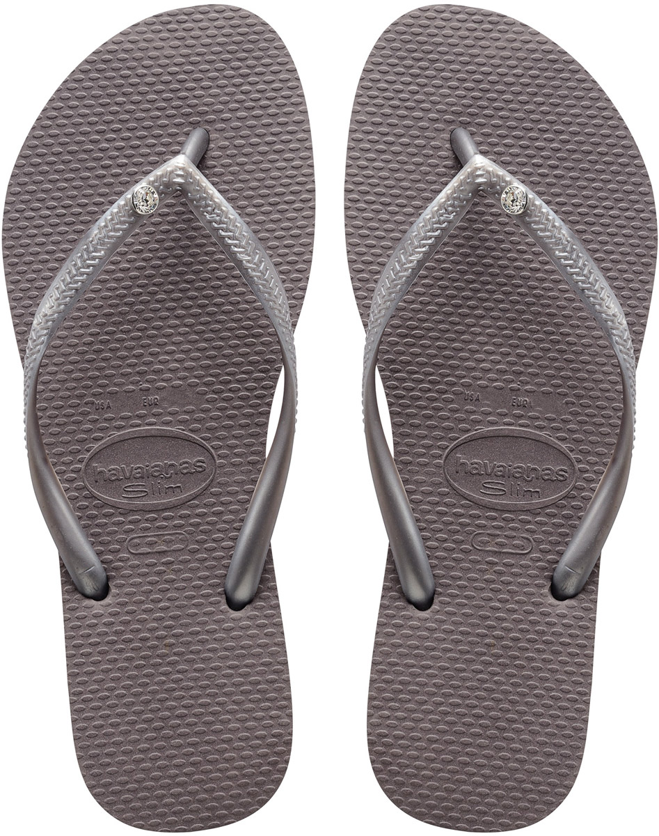 Сланцы женские Havaianas Slim Crystal Glamour SW, цвет: серебряный. 41195175178. Размер 39/40 (40/41)4119517-5178 Сланцы женские Havaianas Slim Crystal Glamour SW, цвет: серебряный. 41195175178. Размер 39/40 (40/41)4119517-5178Модные женские сланцы Slim Crystal Glamour SW от Havaianas придутся вам по душе. Верх модели, выполненный из резины, оформлен названием бренда, рельефным орнаментом и металлическим элементом со стразом. Ремешки с перемычкой гарантируют надежную фиксацию модели на ноге. Подошва выполнена из материала ЭВА. Рифление на верхней поверхности подошвы предотвращает выскальзывание ноги. Рельефное основание подошвы обеспечивает уверенное сцепление с любой поверхностью. Удобные сланцы прекрасно подойдут для похода в бассейн или на пляж.