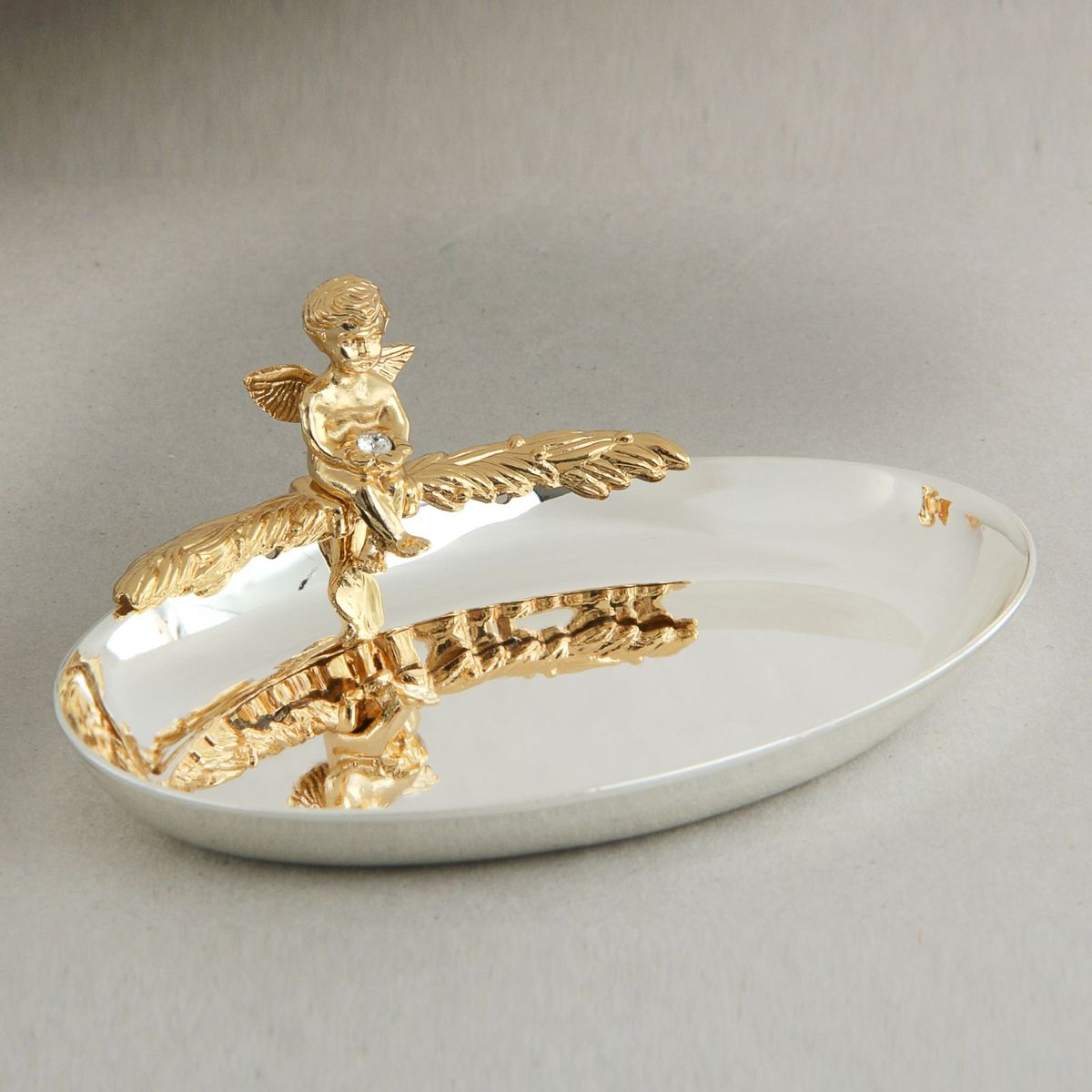 Swarovski Elements Блюдце для колец овал с ангелом 11,5х4х9 смRSP-202S Swarovski Elements Блюдце для колец овал с ангелом 11,5х4х9 смRSP-202SГлавный символ новой семьи – обручальные кольца - требуют особого обращения. К ним, согласно русским обычаям, не должен прикасаться никто кроме молодоженов и матери жениха, которая до бракосочетания должна хранить кольца в своем доме. Чтобы никто из посторонних, поднося кольца, не прикоснулся к ним, нужно блюдце или подушечка.
