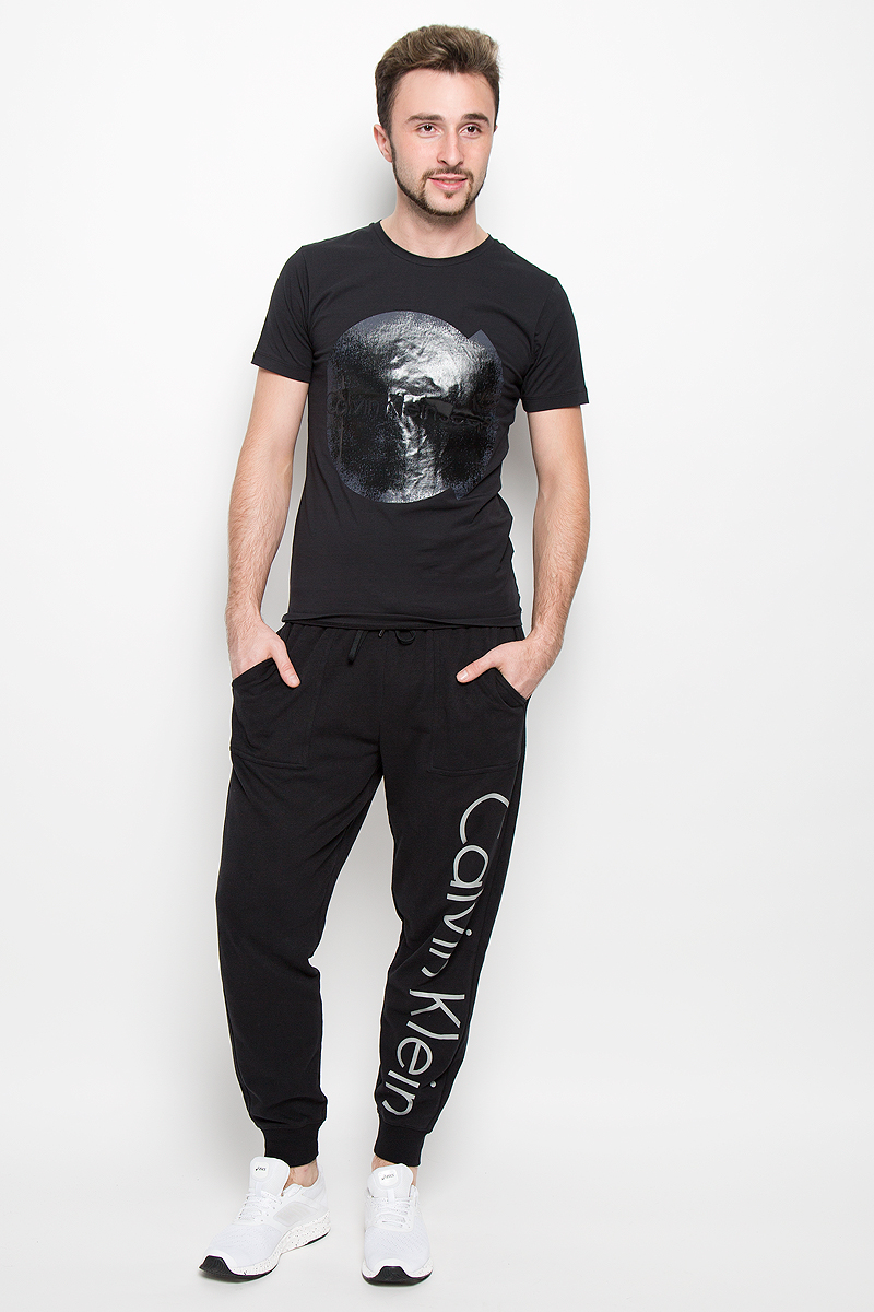 Брюки для дома мужские Calvin Klein Underwear, цвет: черный. NM1263E. Размер M (48)NM1263E_001 Брюки для дома мужские Calvin Klein Underwear, цвет: черный. NM1263E. Размер M (48)NM1263E_001Мужские брюки для дома Calvin Klein Underwear выполнены из хлопка с добавлением полиэстера. Изнаночная сторона изделия с теплым начесом. Эластичный пояс с затягивающимся шнурком позволяет отрегулировать посадку точно по фигуре. Спереди расположены два втачных кармана. Низ брючин дополнен трикотажными манжетами. Оформлено изделие термоаппликацией в виде надписи.